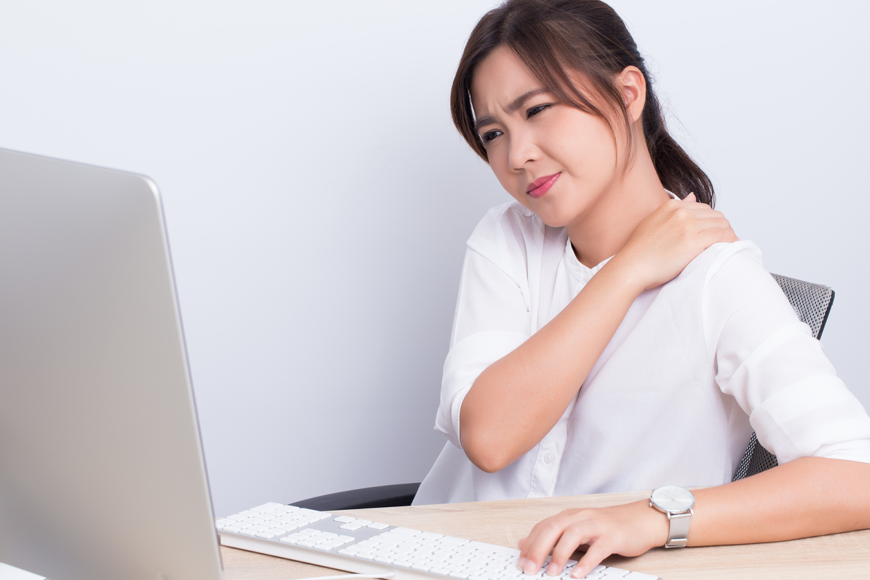 mulher sentada em frente ao computador com tendinite no ombro